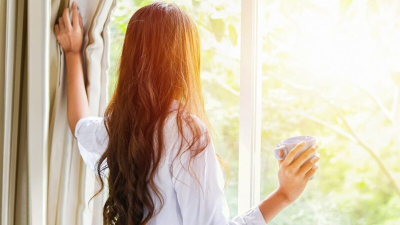 カーテンを開ける女性